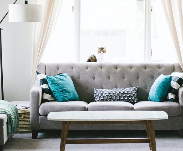 白色抬燈旁有一灰色長沙發後有落地窗